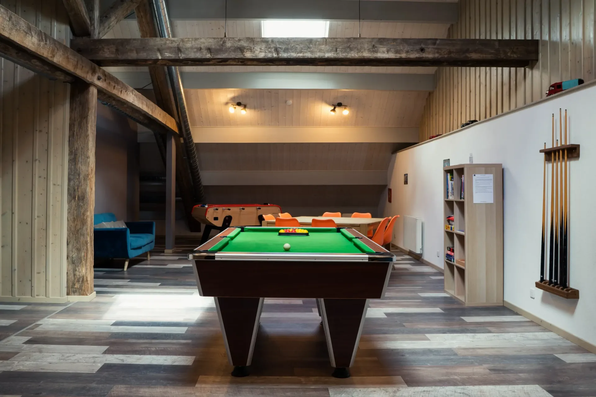 Salle de jeux mansardée avec billard, baby-foot et coin canapé bleu