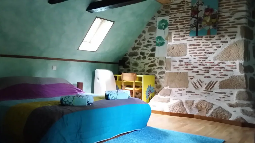 Chambre mansardée aux tons turquoise avec lits doubles sous charpente en bois
