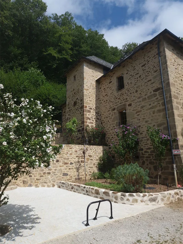 Piscine extérieure chauffée avec transats bleus face à la façade en pierre du gîte