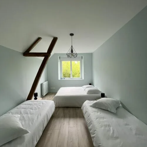 Chambre mansardée avec poutre apparente et plusieurs lits