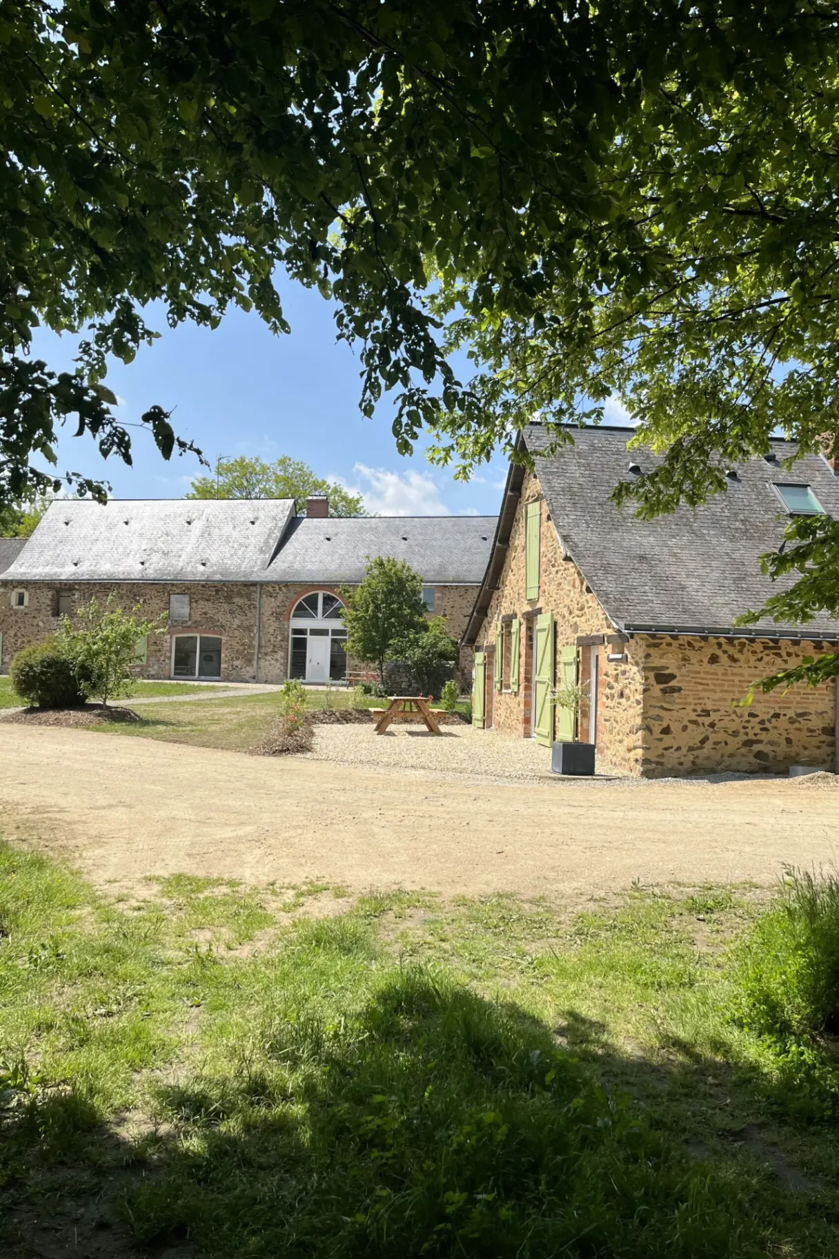 Bâtiments en pierre du gîte avec toitures d'ardoise et cour engazonnée