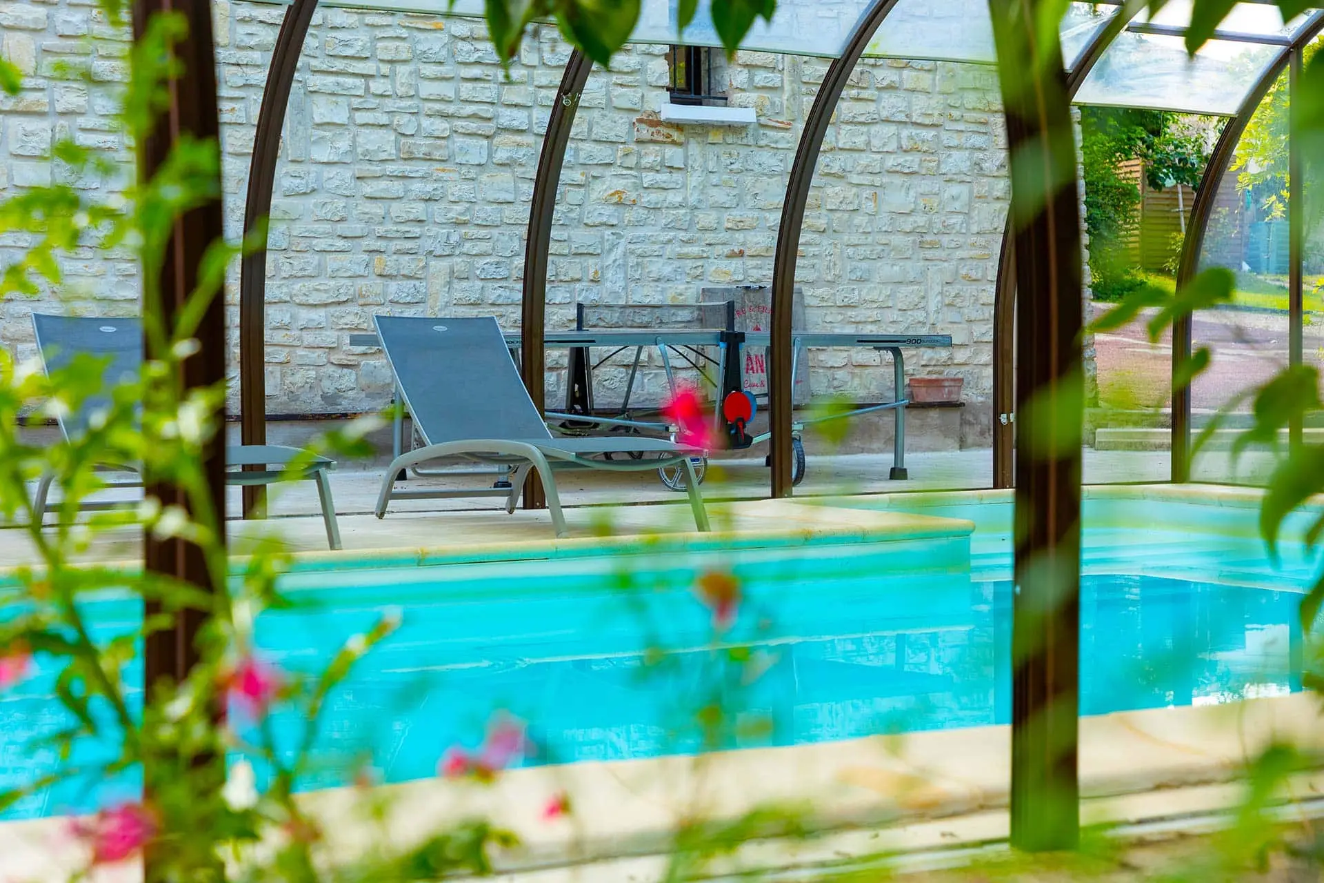 Piscine intérieure sous véranda avec tennis de table et transats