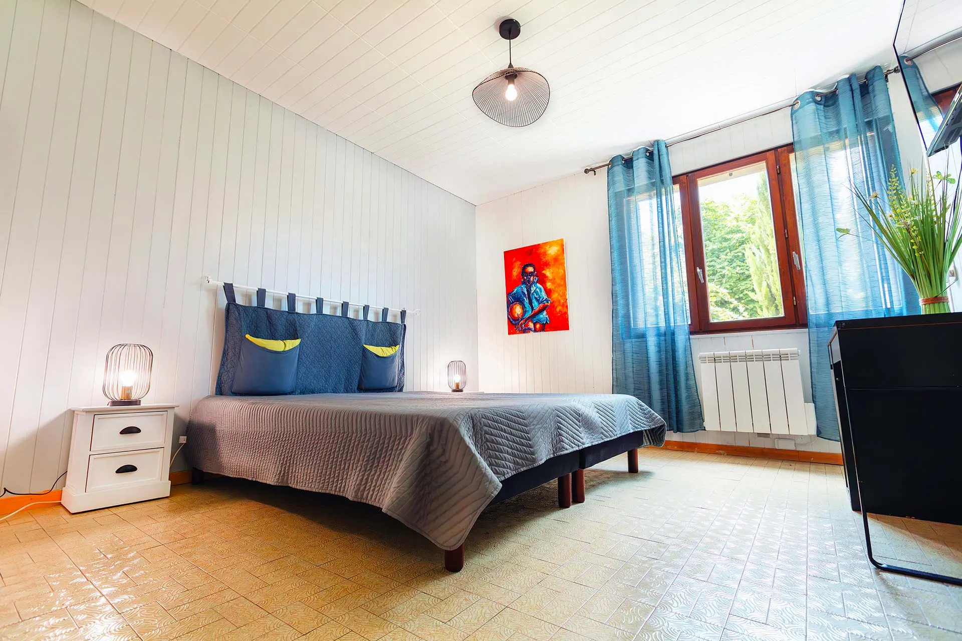 Chambre avec lit double, tête de lit capitonnée et papier peint végétal