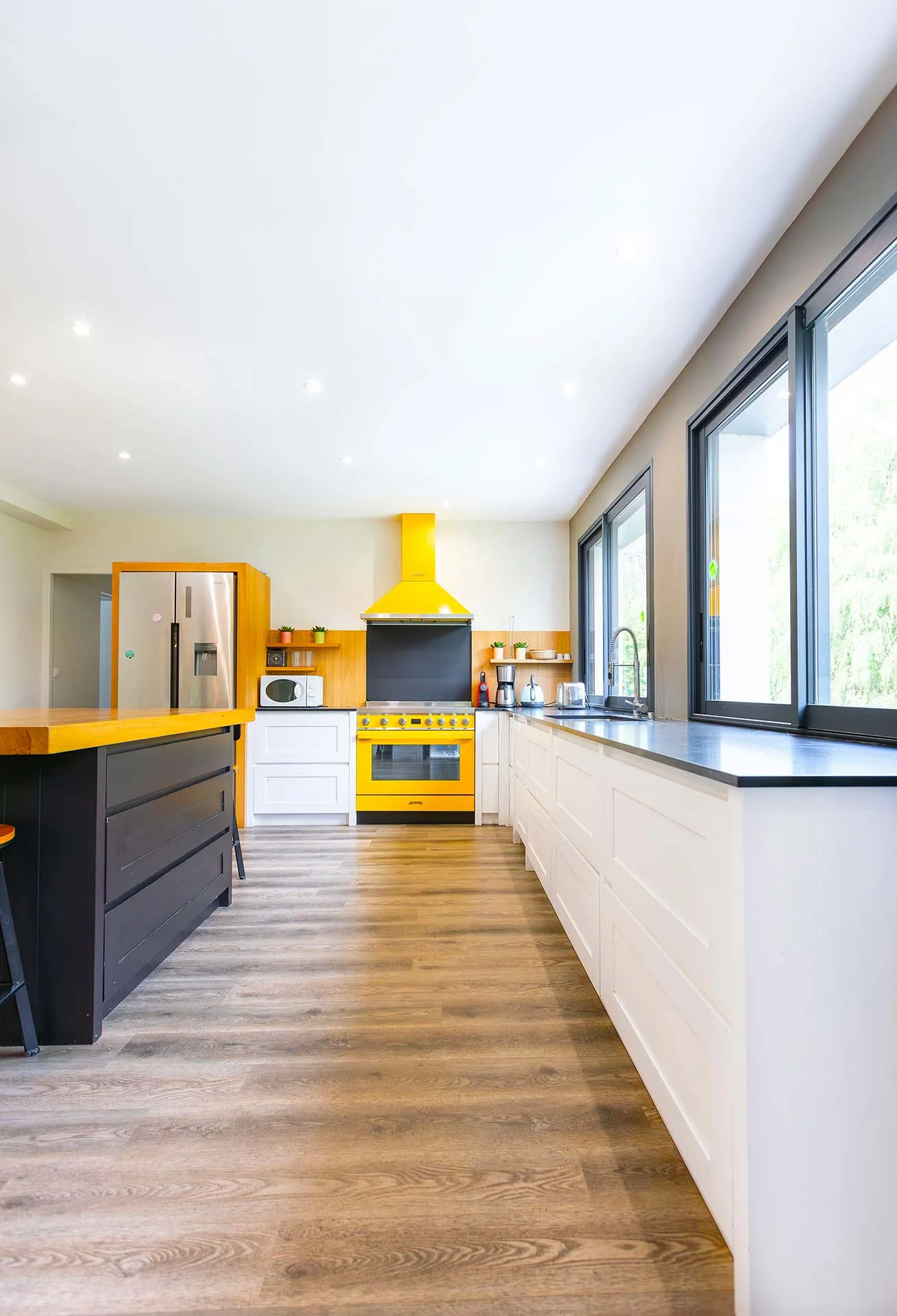 Cuisine équipée jaune avec piano de cuisson et grand plan de travail