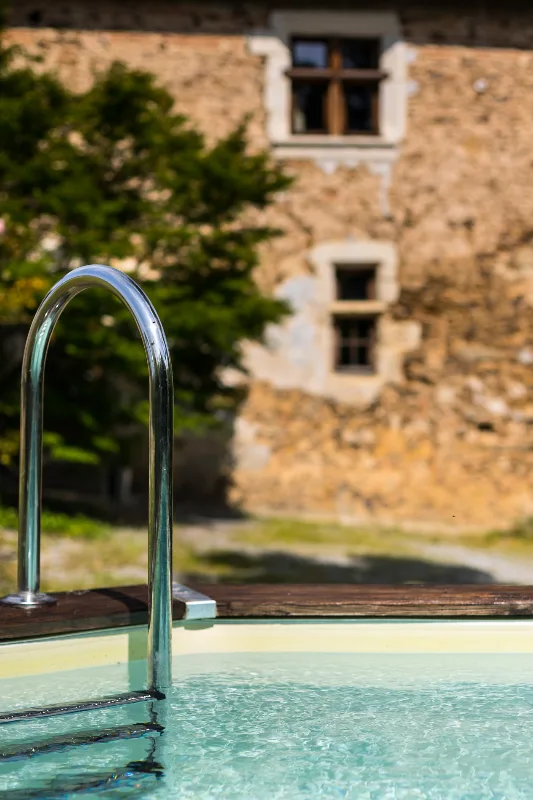 Détail de la piscine avec la façade en pierre ancienne en arrière-plan