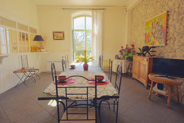 Salle à manger aux murs en pierre avec cheminée et grande table conviviale