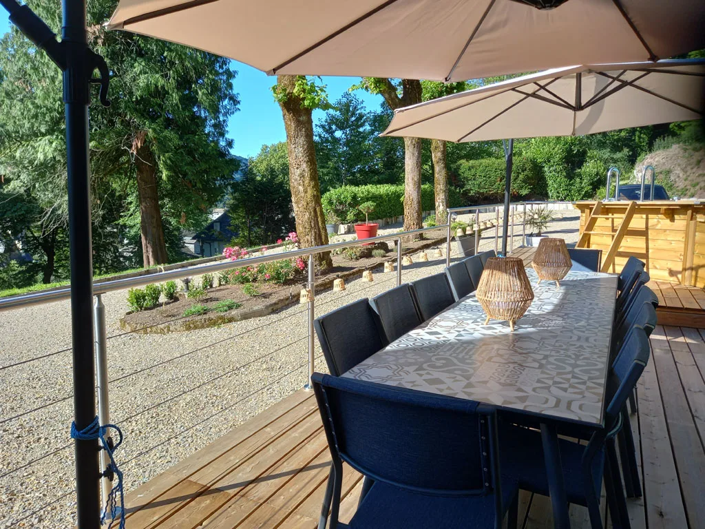 Terrasse avec spa extérieur, salon de jardin et transats sous les arbres