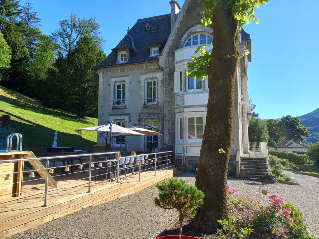 Façade latérale de la demeure de style château au milieu d'un jardin en pente