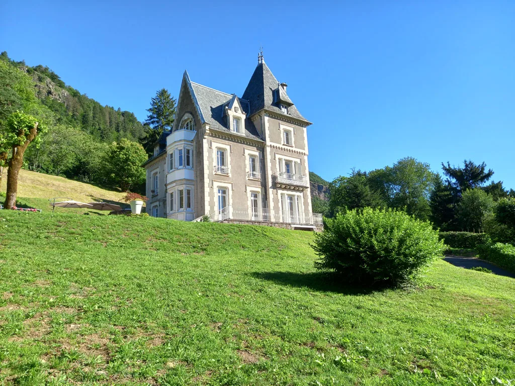 Vue éloignée de la demeure dans son parc arboré au pied des montagnes