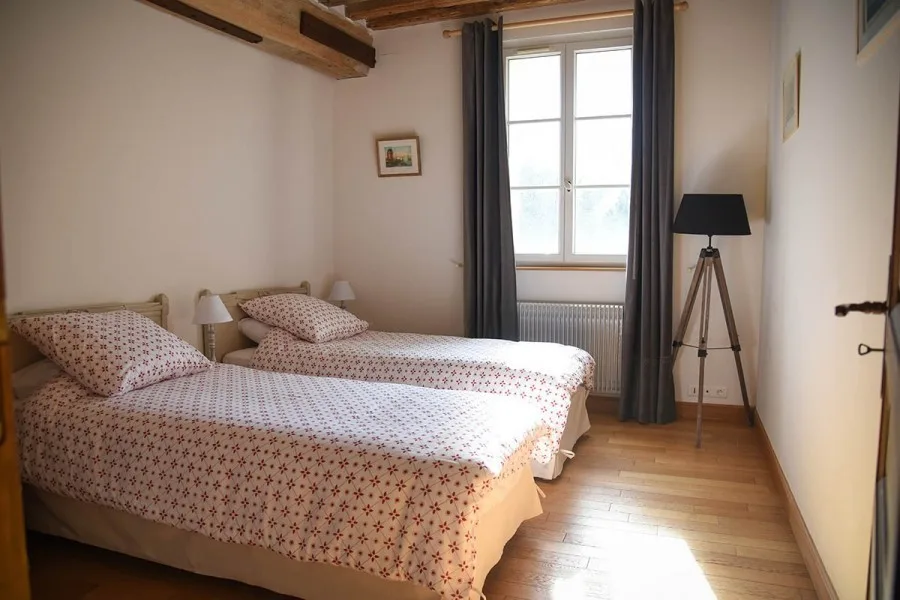 Chambre double avec tête de lit ancienne et rideaux gris