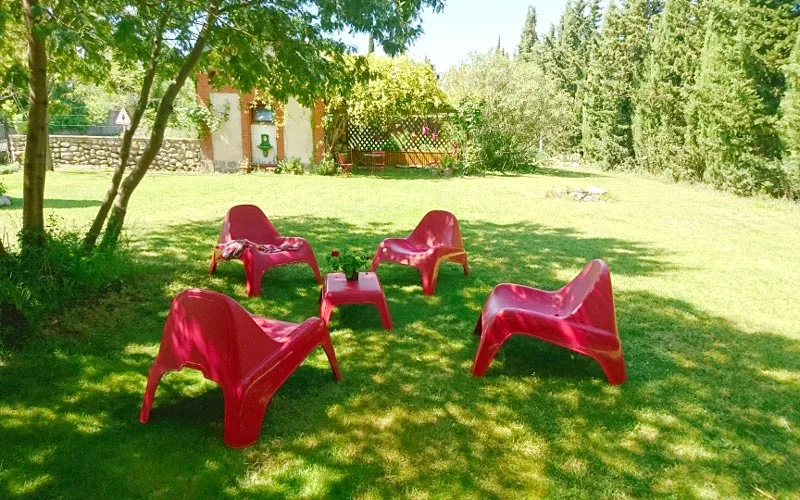 Terrasse ombragée et jardin avec salon extérieur et vue sur le mur en pierre