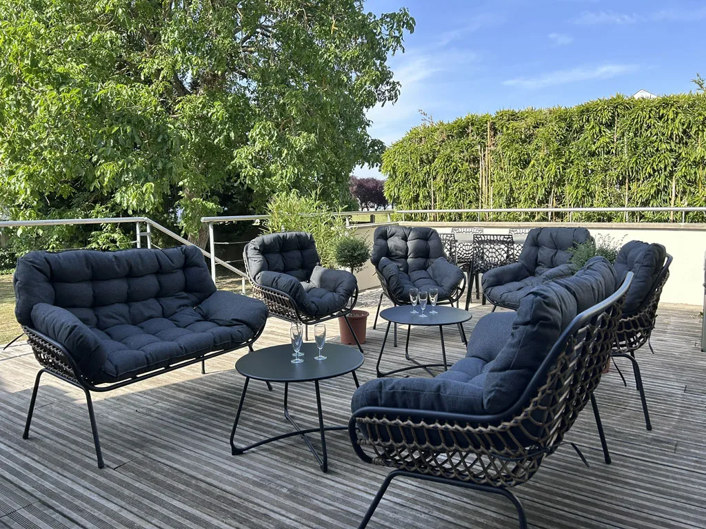 Terrasse extérieure avec salon de jardin et coussins bleus pour se détendre en groupe