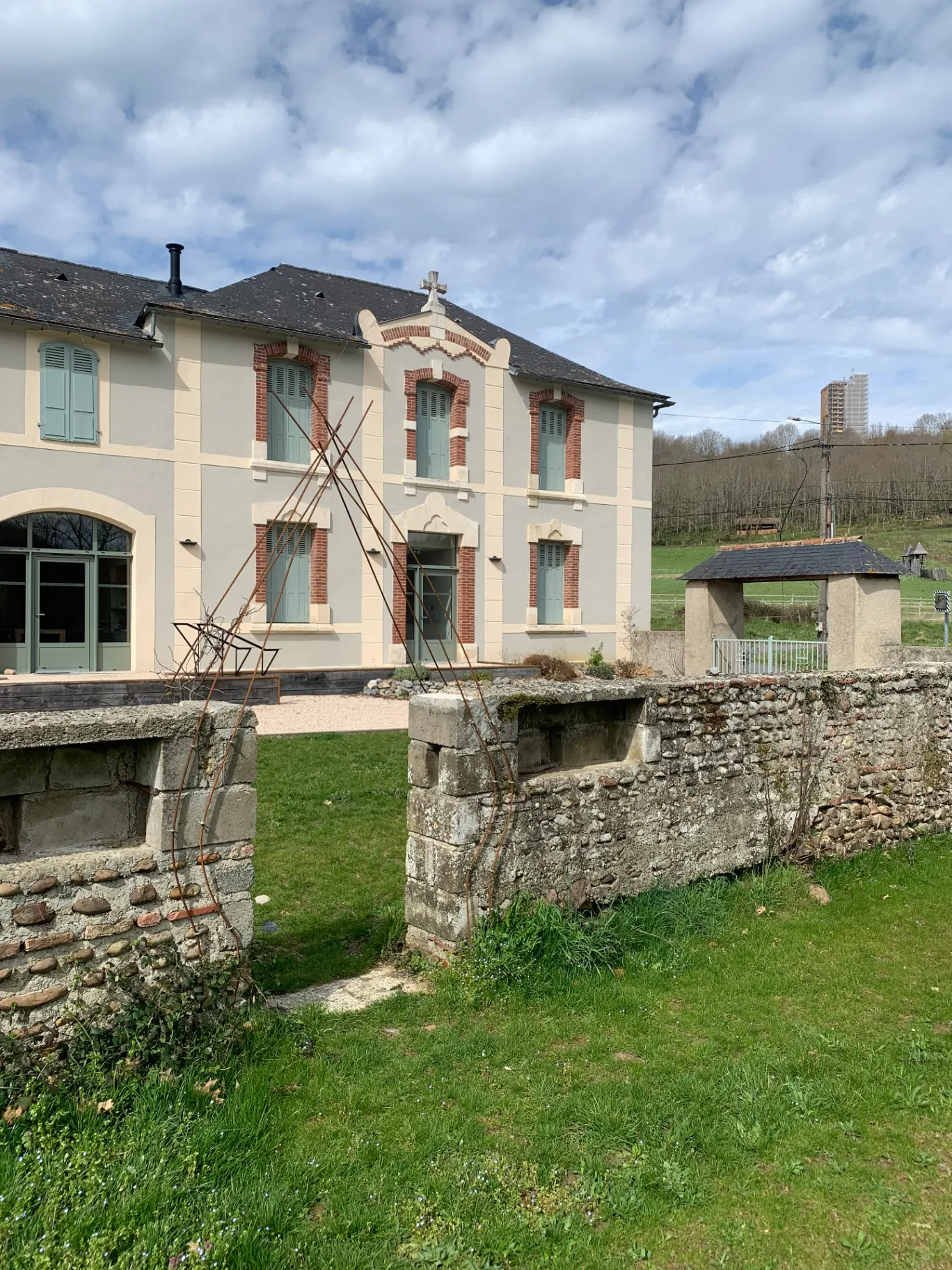 Façade du gîte de groupe avec son jardin clos en pierre et vue sur la campagne béarnaise