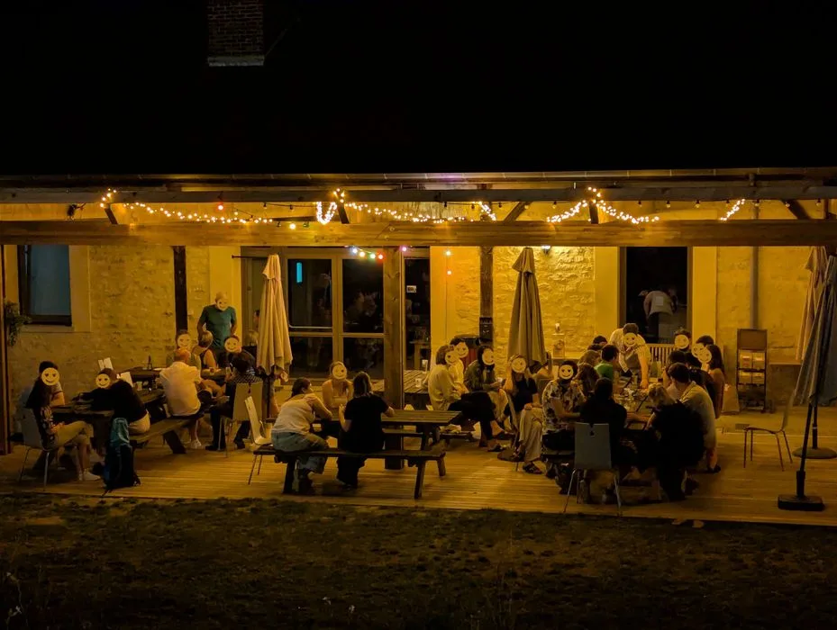 Terrasse couverte illuminée en soirée avec grandes tablées conviviales