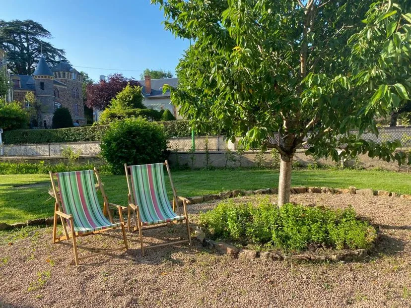 Jardin arboré avec transats et vue sur un château voisin