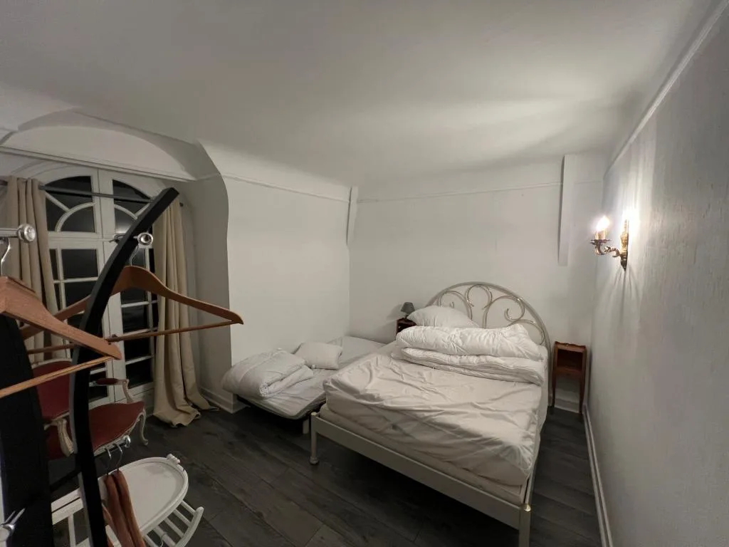 Chambre avec lit double en fer forgé et lit d'appoint, parquet sombre