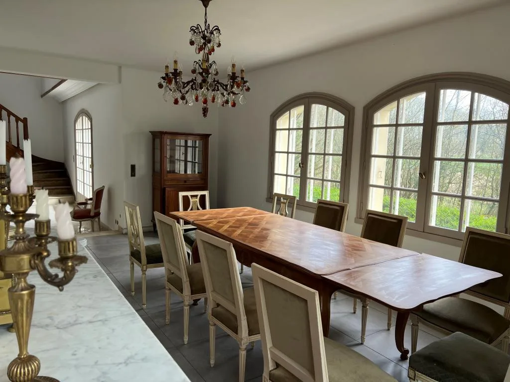Grand séjour et salle à manger avec table en bois pour dix convives et fenêtres arrondies