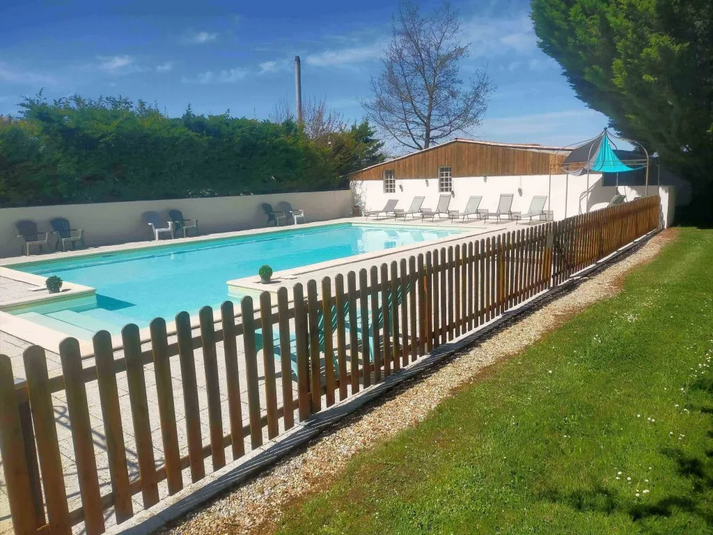 Grande piscine extérieure du domaine avec plage engazonnée et transats