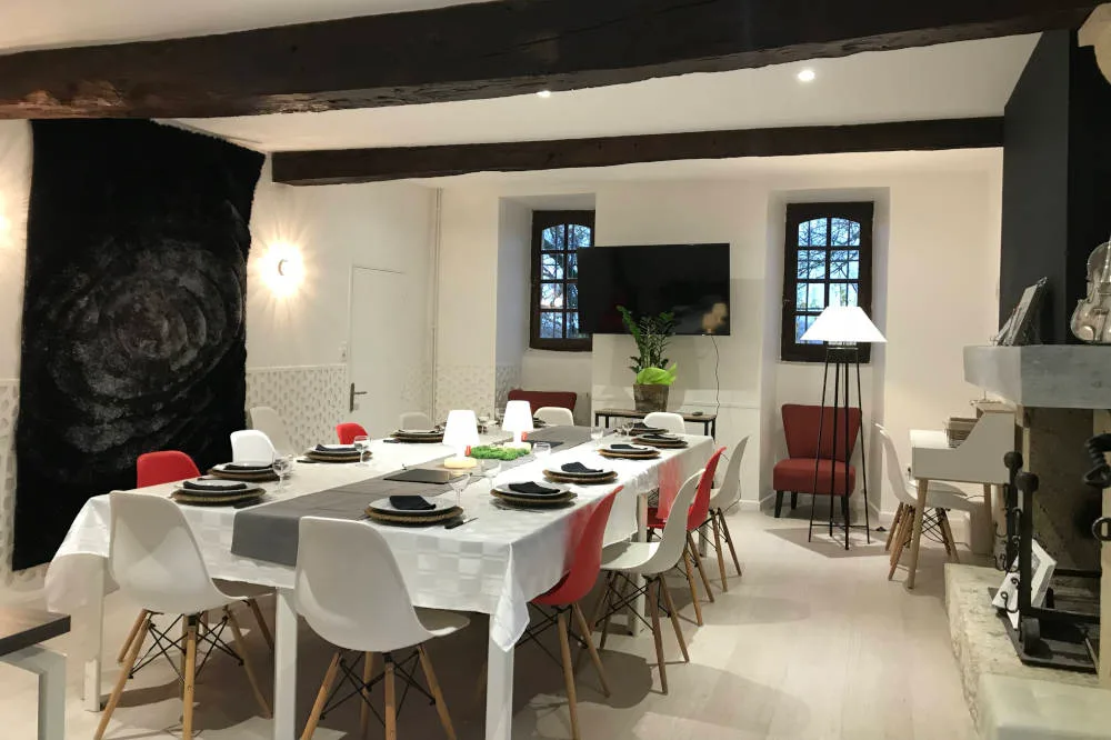Salle à manger intérieure avec longue table dressée en blanc pour recevoir un grand groupe