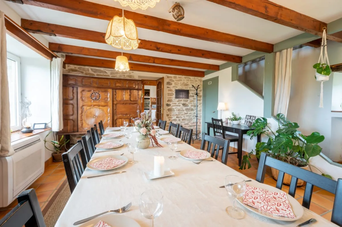 Salle à manger avec poutres apparentes et table dressée pour un repas convivial