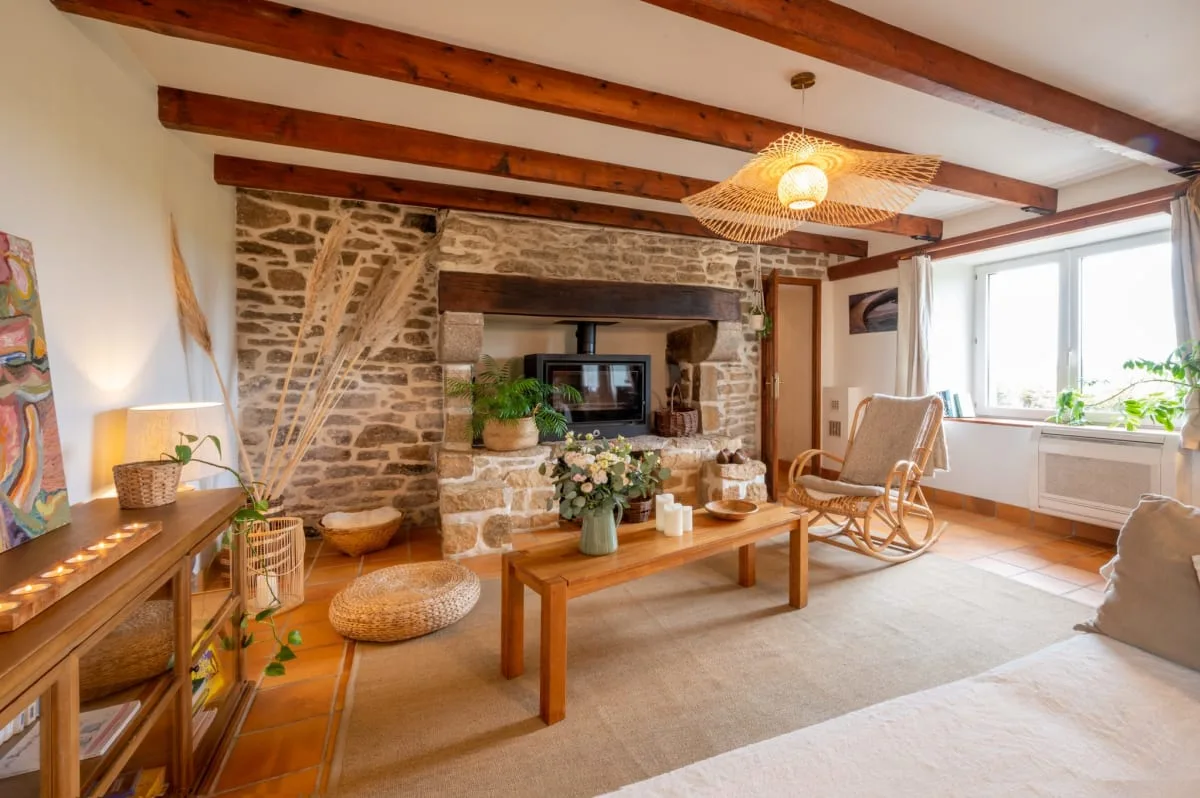 Séjour spacieux avec cheminée en pierre apparente, poutres en bois et mobilier moderne