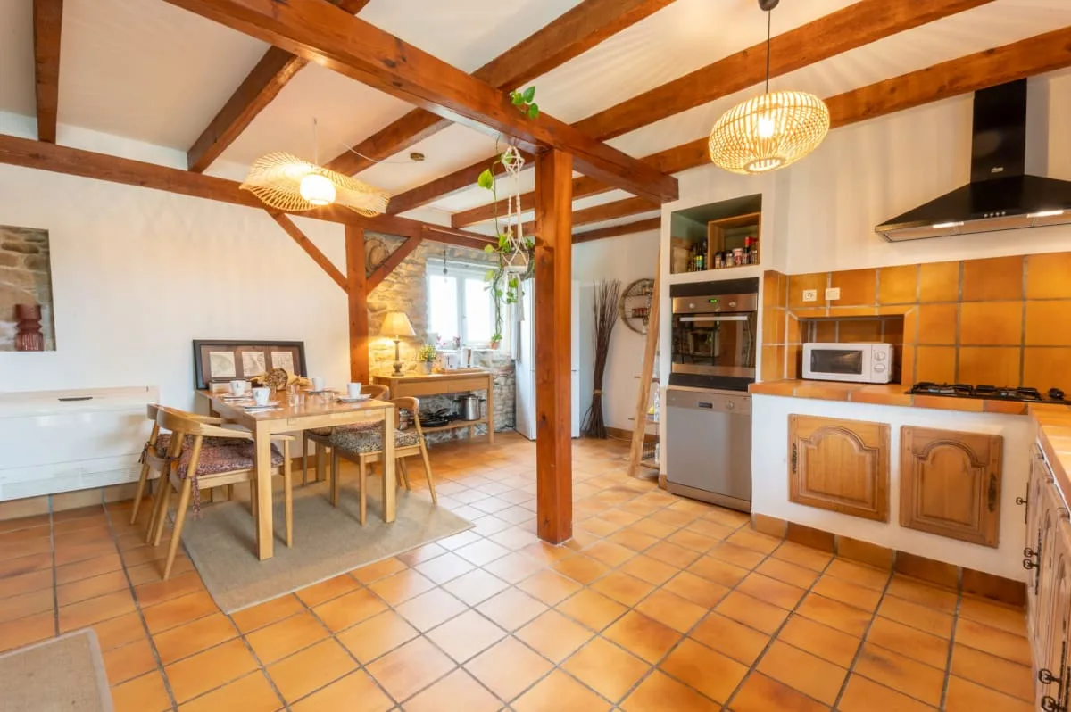 Cuisine et salle à manger ouvertes avec poutres en bois et carrelage en terre cuite