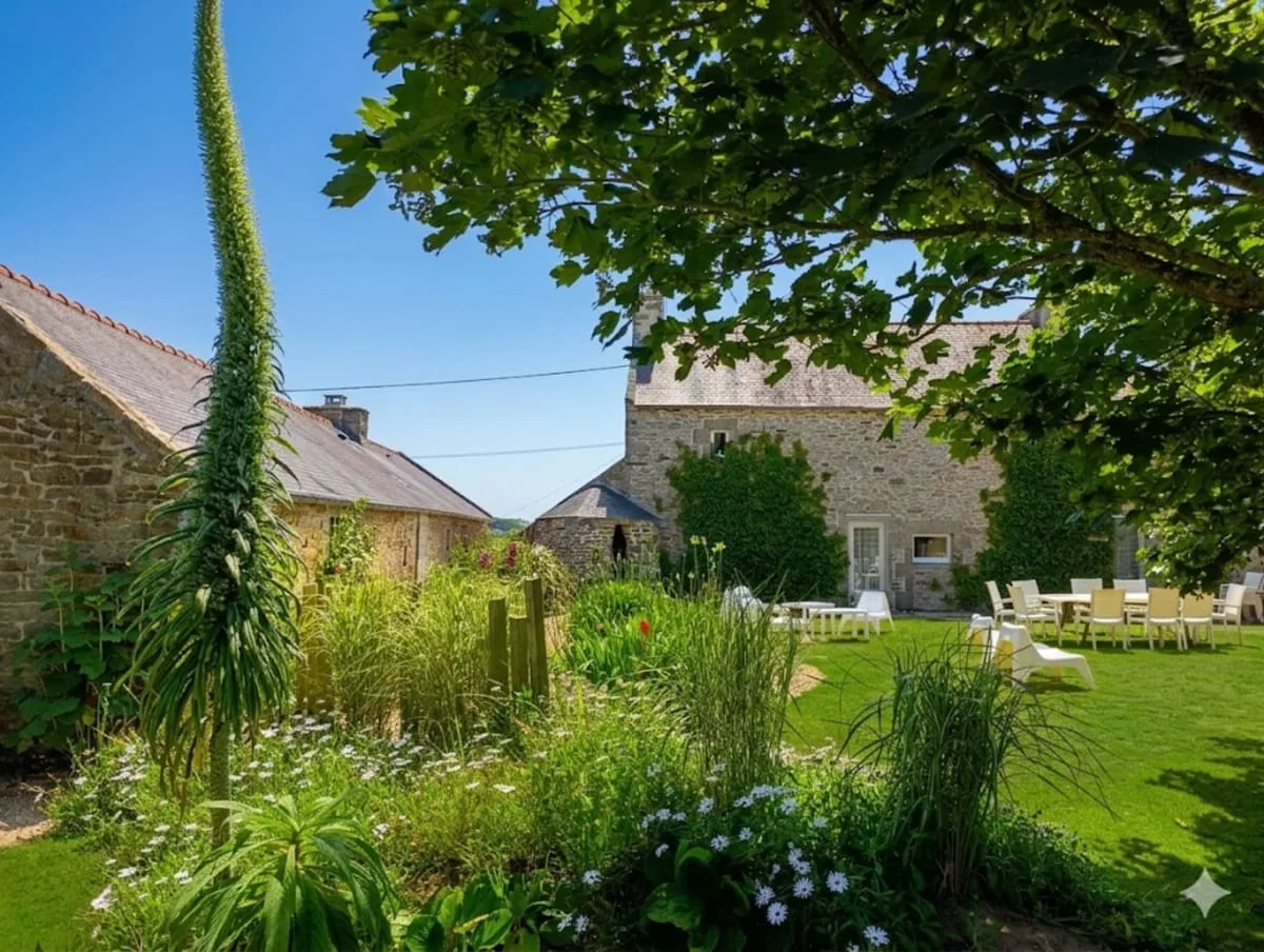 Vue du jardin de Ker Gana avec bâtisses en pierre, pelouse verdoyante et arbre ombragé