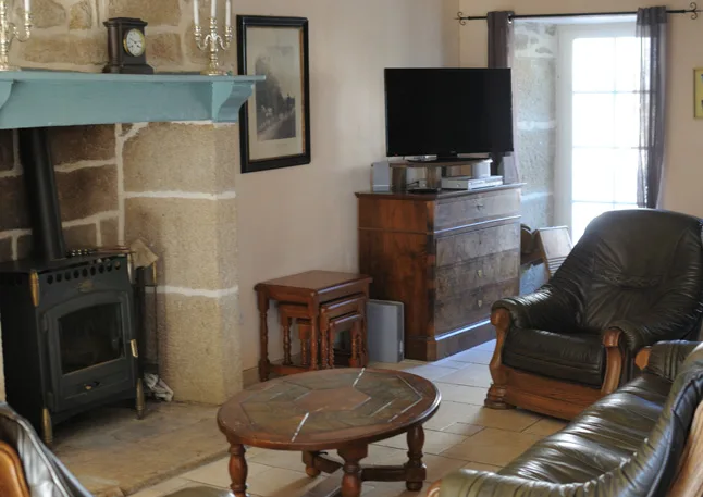 Salon avec poêle à bois sur cheminée en pierre, fauteuils et canapé en cuir