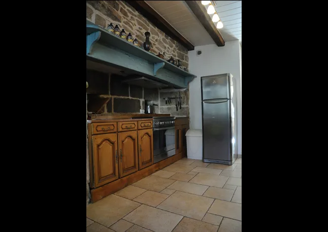 Cuisine campagnarde avec étagère bleue sur mur en pierre et réfrigérateur inox