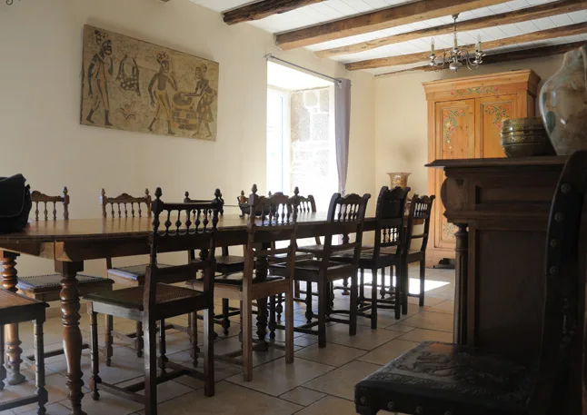 Grande salle à manger avec longue table en bois pour repas de groupe et cheminée en pierre