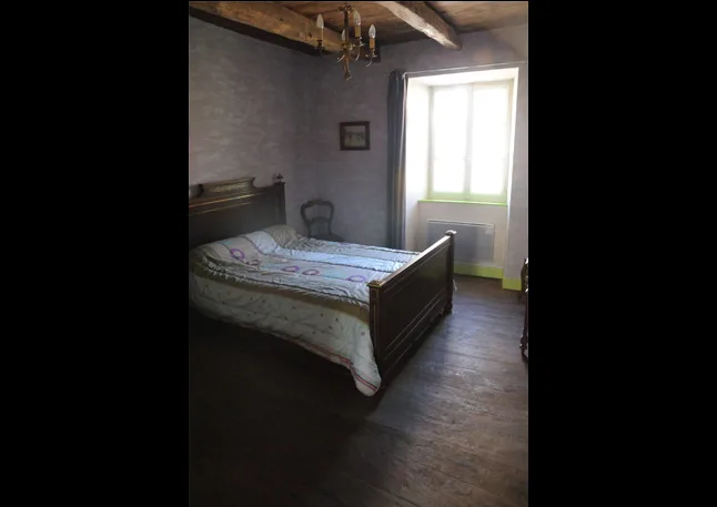 Chambre avec grand lit ancien en bois et parquet, sous poutres apparentes