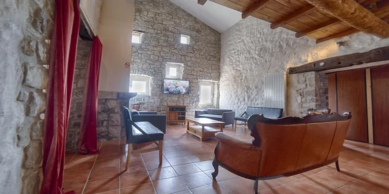 Salon avec canapés et coin télévision, ambiance chaleureuse aux murs en pierre