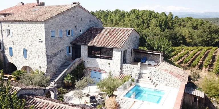 Gîte de groupe Mas St-Alban à Saint-Alban-Auriolles — Vue aérienne du grand mas en pierre avec sa cour, son terrain et son environnement de collines, capacité 15 personnes