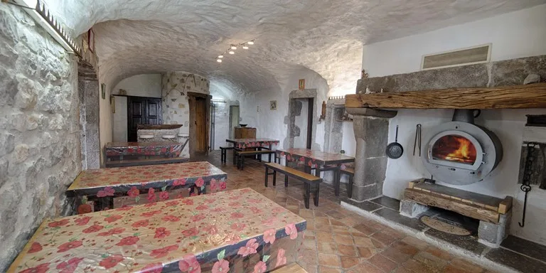 Grande salle à manger avec cheminée en pierre, poutres apparentes et longue table
