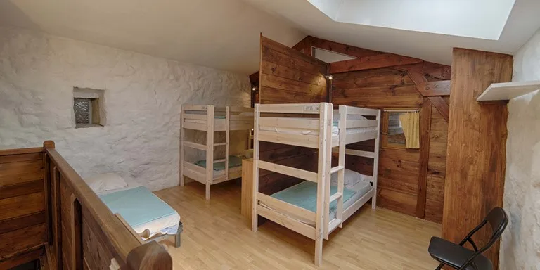 Chambre dortoir avec lits superposés sous charpente en bois