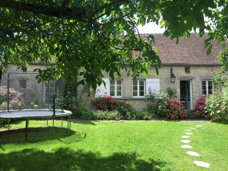 Façade en pierre de la maison entourée de verdure et d'un jardin arboré