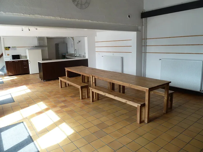 Grande salle polyvalente aménageable avec mobilier léger pour repas et réunions de groupe