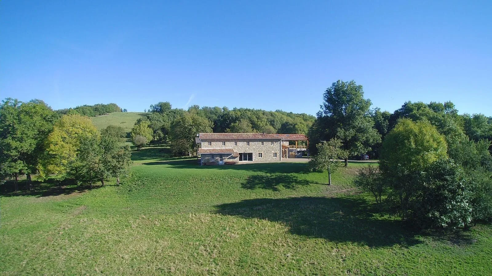 Gîte de groupe Gîte de Caville à Montesquieu-Avantès — Vue aérienne de la bâtisse en pierre du gîte de Caville entourée d'un grand parc arboré, capacité 15 personnes