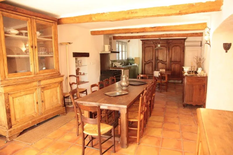 Cuisine provençale avec poutres apparentes, buffet ancien et grande table conviviale
