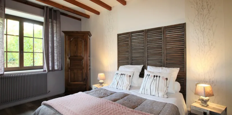 Chambre avec lit double, poutres apparentes et vue sur le jardin