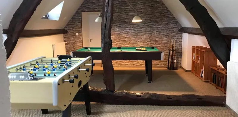 Salle de jeux avec billard et baby-foot sous charpente apparente