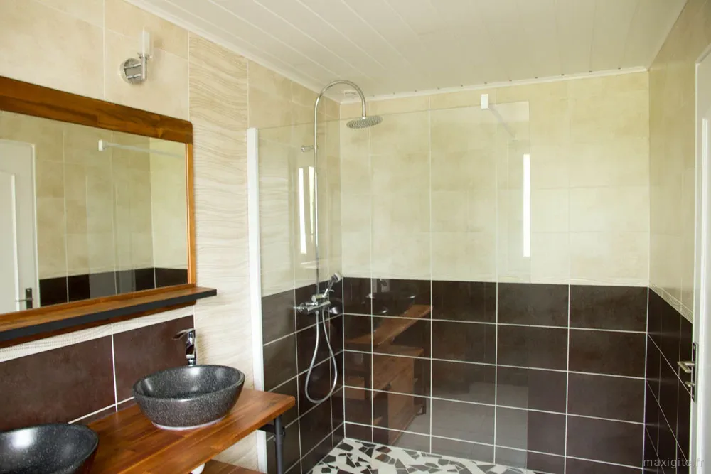 Salle de bains carrelée avec double vasque et grand miroir