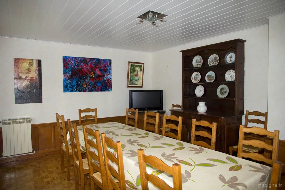 Salle à manger avec grande table ronde et nappe fleurie pour les repas en groupe
