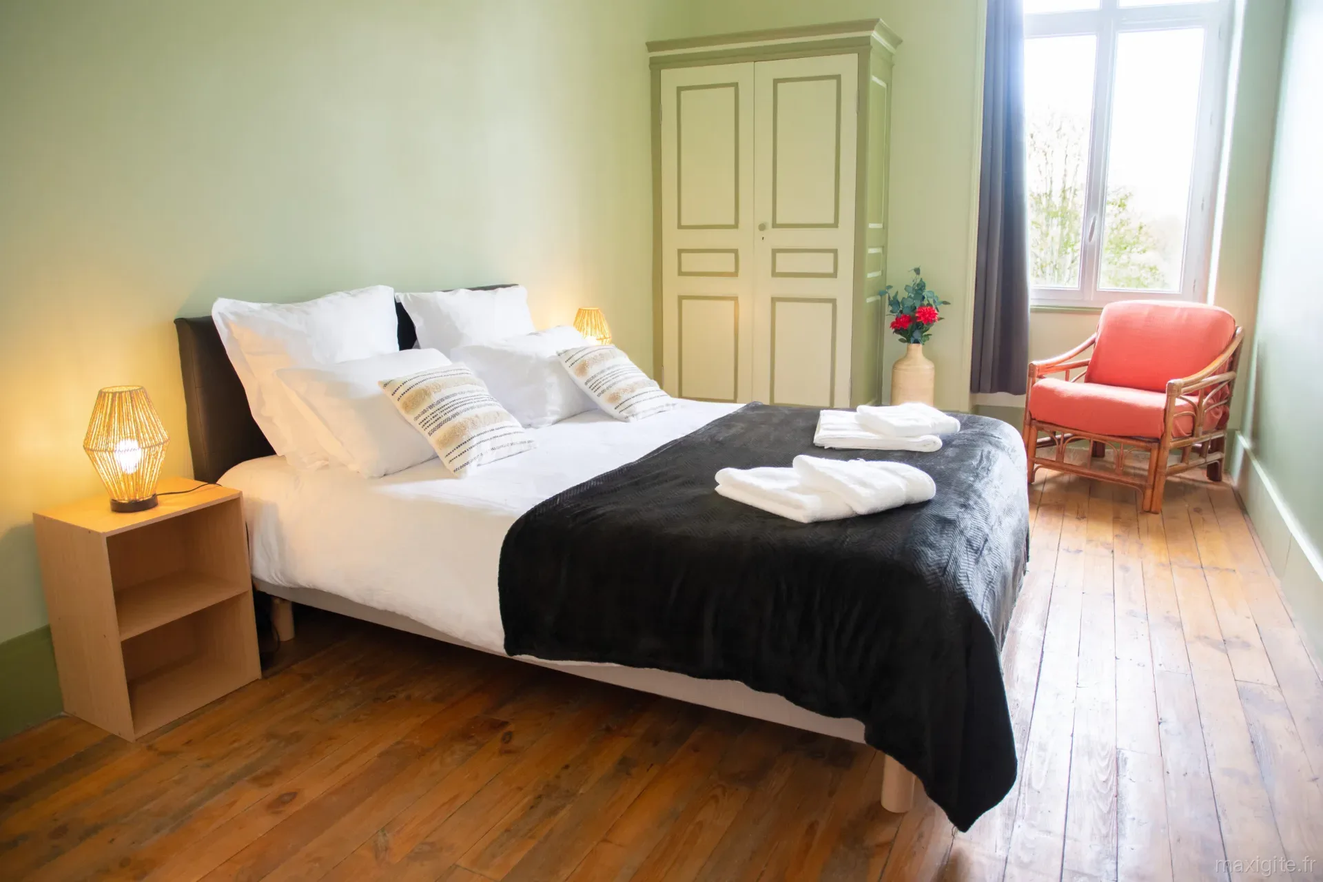 Chambre lumineuse aux murs verts avec fauteuil orange, décoration graphique et fenêtre haute