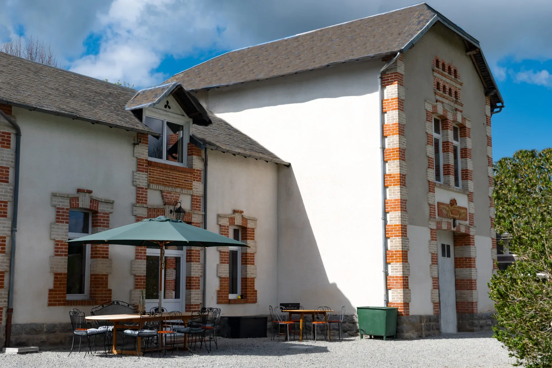 Cour intérieure du château avec grandes tables en bois, chaises en fer forgé et parasol
