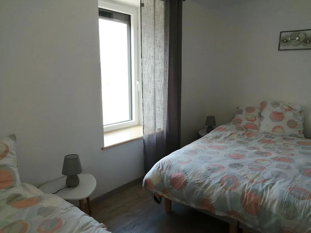 Chambre double avec couette à motifs, fenêtre lumineuse et tables de chevet