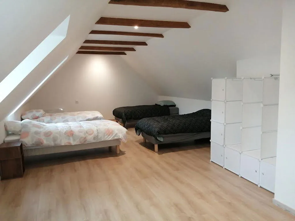 Dortoir sous charpente avec plusieurs lits simples et rangements modulables blancs