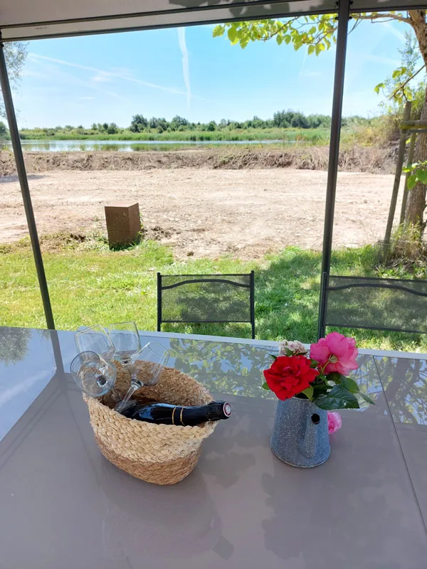 Terrasse couverte avec table dressée face à l'étang privé du domaine