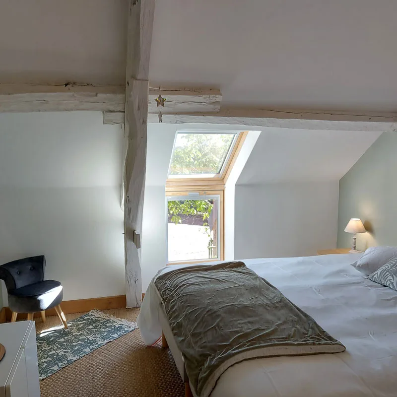 Chambre mansardée lumineuse avec lit double, lit bébé et fenêtre de toit
