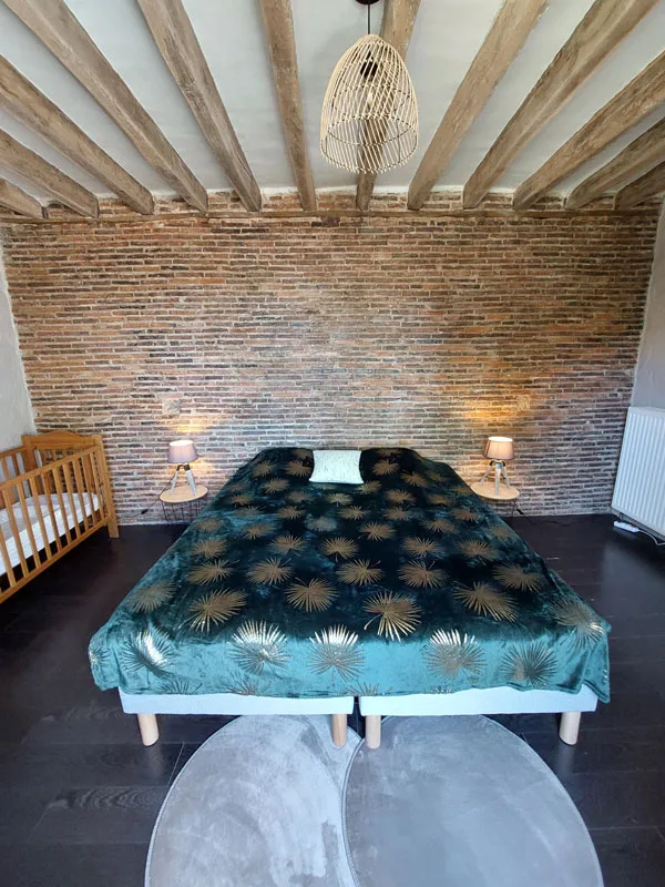 Chambre double avec tête de lit en briques et mobilier chaleureux